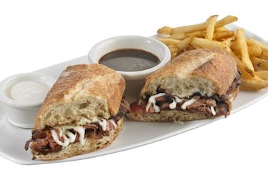French dip sandwich with small cups of horseradish and au jus.