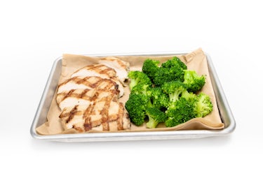 image of sliced, grilled chicken on a sheet tray with broccoli florets.