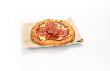 Image of kid's pepperoni pizza on a sheet pan and brown parchment paper.