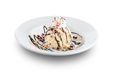 Image of vanilla ice cream with chocolate drizzle, sprinkles, and whipped cream.