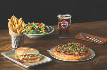 imge of a side salad, indy pizza, side of fries, pepsi and half sandwich.