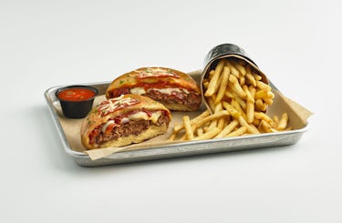 image of pizza burger cut in half with a side of french fries.
